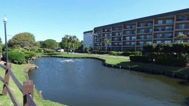 A hotel with a swimming pool, surrounded by greenery and a clear sky. - Myrtle Beach Resort B-229 (Myrtle Beach)