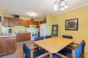 Eine Küche mit Holzausstattung, einem Esstisch mit Stühlen, einem Kühlschrank und einer an der Wand angelehnten Leiter.