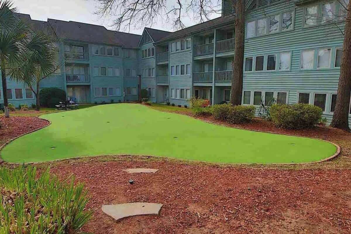 A residential building with a green lawn and a small pool.