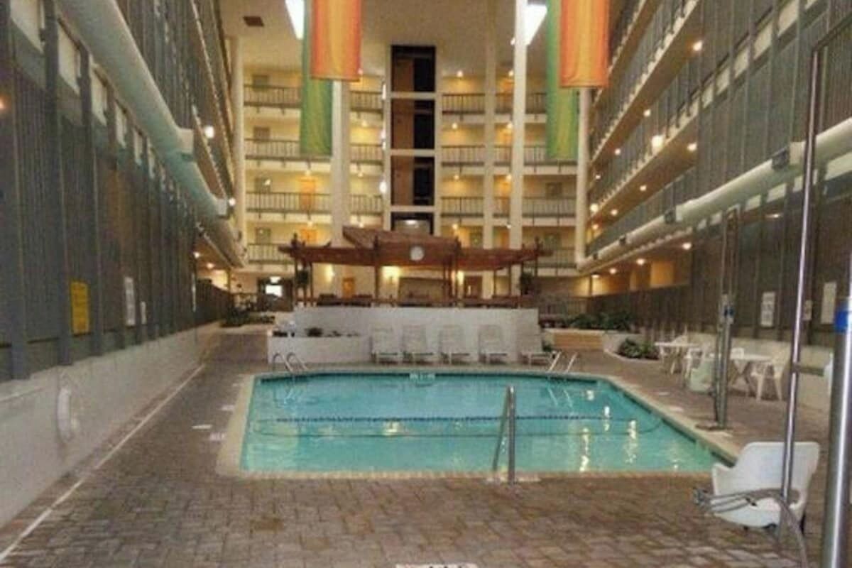 L’intérieur d’un hôtel comprenant un espace central avec piscine, plusieurs étages dotés de balcons et un espace de détente couvert.