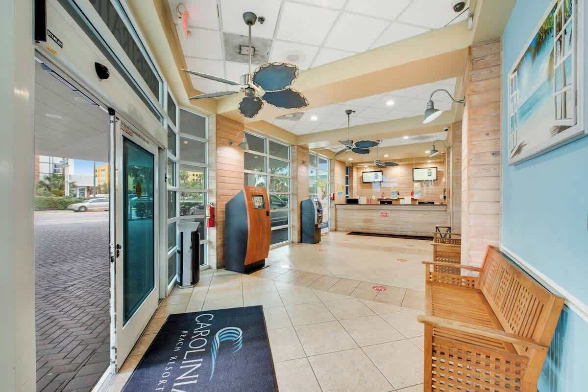 A hotel lobby with a reception desk, seating area, and a view of the street.