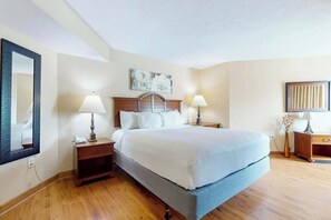 A hotel room with a bed, bedside tables, lamps, a mirror, and artwork on the walls. - Carolinian Beach Resort 1734 (Myrtle Beach)
