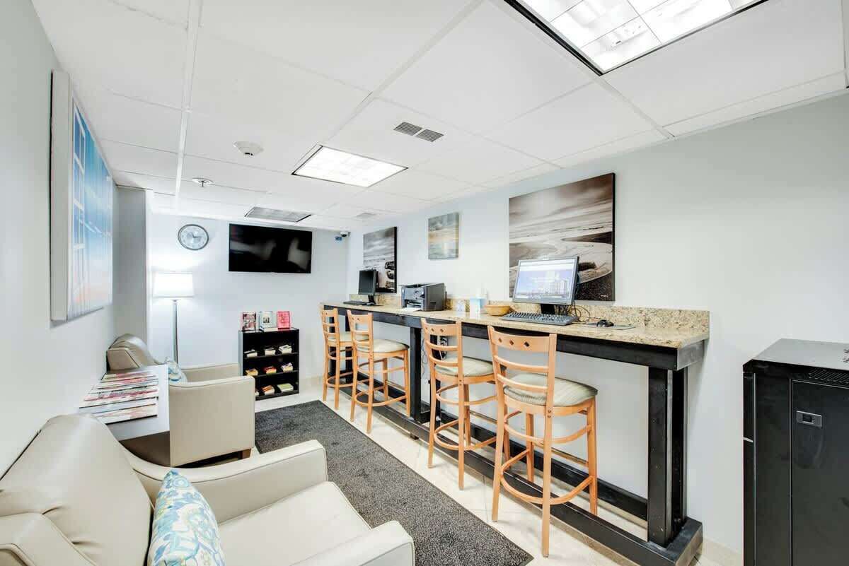 A modern office space with a bar area, seating, and a television.