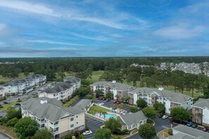 A residential area with multi-story buildings, a swimming pool, and a parking lot. - Magnolia Pointe Unit 305 (Myrtle Beach)
