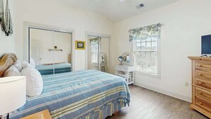 A bedroom with a bed, a dresser, a vanity with a mirror, and a ceiling fan. - Magnolia Pointe Unit 305 (Myrtle Beach)
