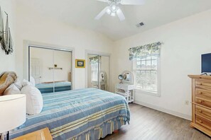 Ein Schlafzimmer mit Bett, Schminktisch, Kommode und Deckenventilator.