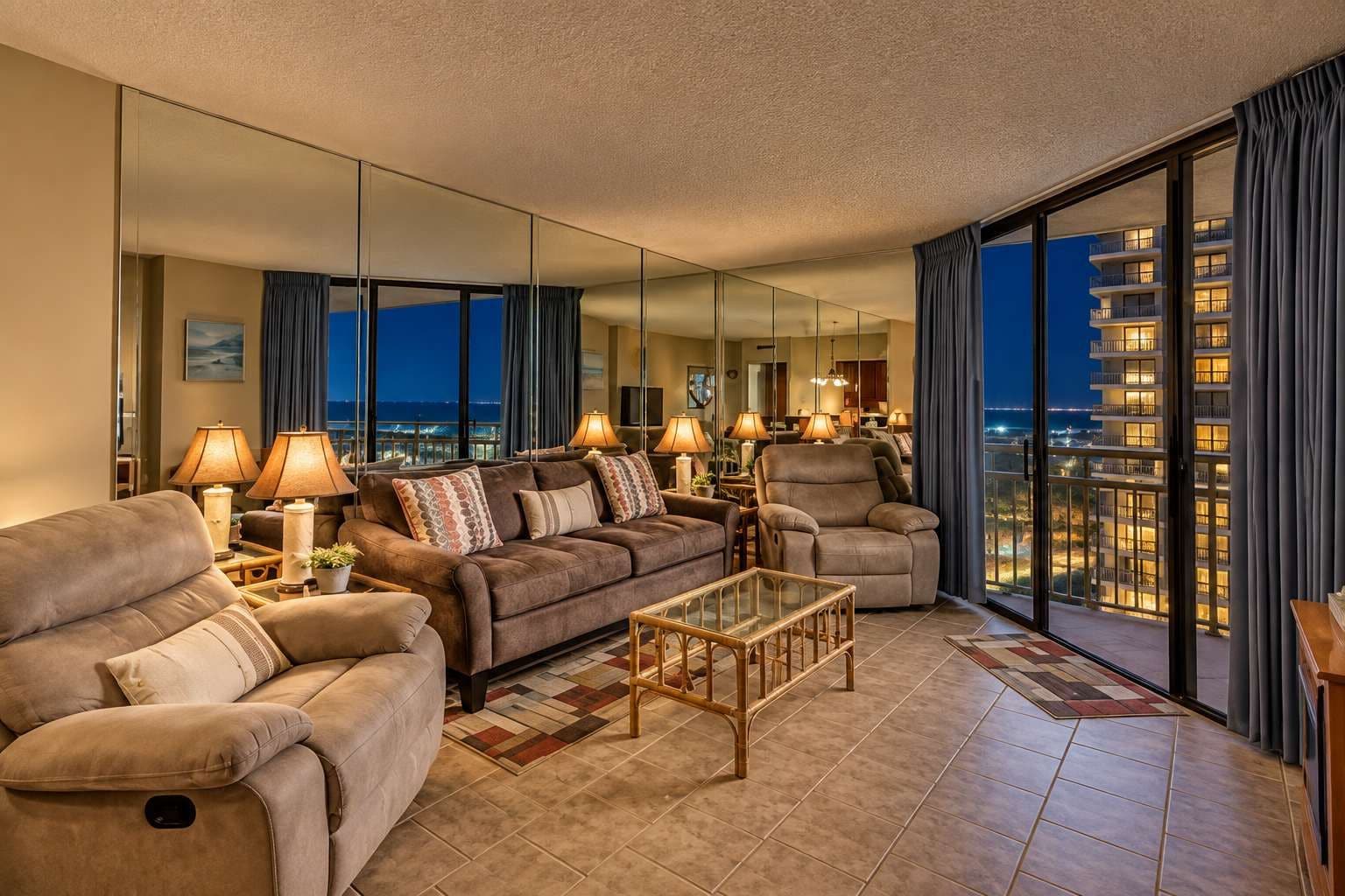 Ein geräumiges Wohnzimmer mit einer großen Couch, Sesseln, einem Couchtisch und Blick auf eine nächtliche Stadtansicht.