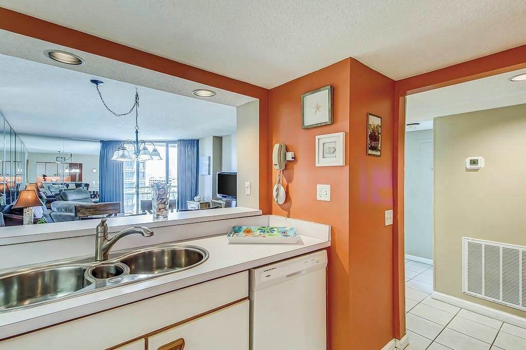 A modern kitchen with a built-in dishwasher, a sink, and a mirror above the countertop.