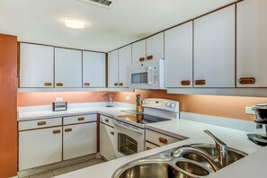 Uma cozinha com armários brancos, micro-ondas, forno e pia.