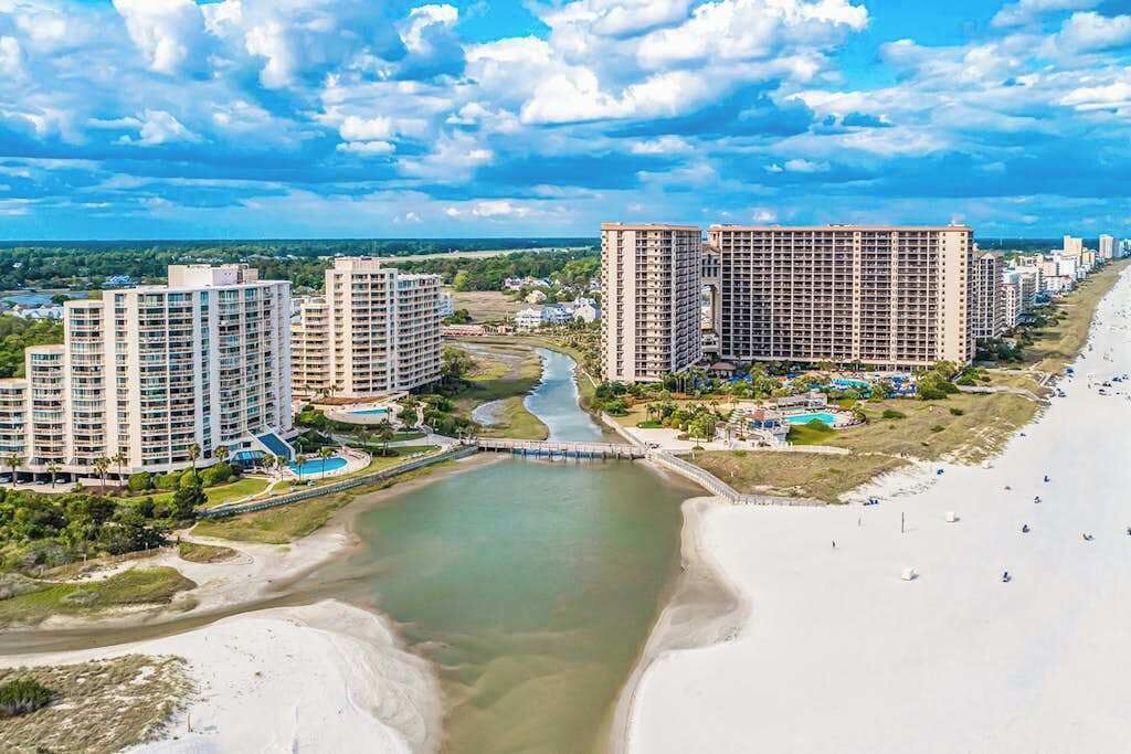 A coastal resort area with high-rise buildings, a beach, and a river.