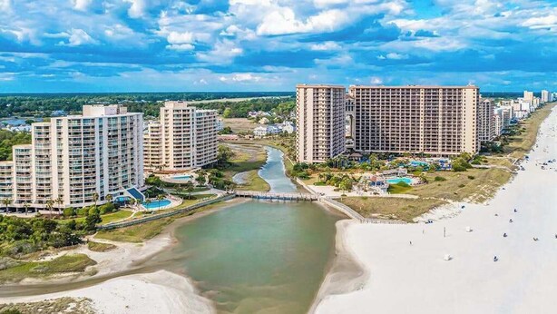 Een kustresort met hoge gebouwen, een strand en een rivier.
