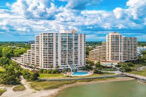 Ein hoch aufragendes Hotel mit mehreren Stockwerken, einem Pool und einem Strandbereich.