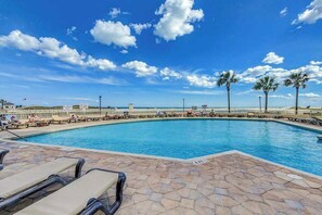 A swimming pool with lounge chairs and palm trees, surrounded by a fence. - Ocean Creek Plantation DD-6 (Myrtle Beach)
