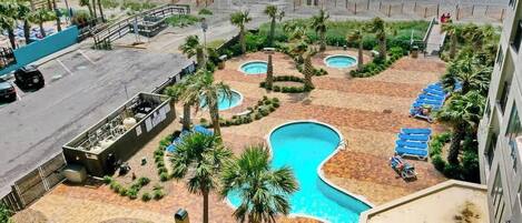 A resort with multiple swimming pools, palm trees, and a beach view.