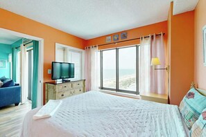 A bedroom with a bed, a television, a window with curtains, and a view of the outside. - Palace Resort Unit 813 (Myrtle Beach)