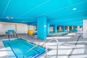 Ein Schwimmbeckenbereich mit mehreren Pools, blauer Decke und Liegestühlen.