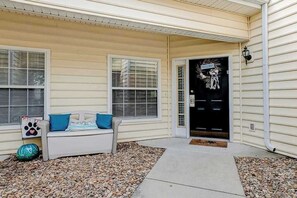 A house with a porch, a white couch with blue cushions, and a black door with a decorative wreath. - Legends Resort - Montrose C (Myrtle Beach)