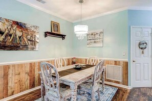 Ein Esszimmer mit holzgetäfelter Wand, einem Chandelier und Kunstwerken.