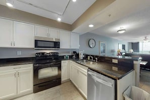 A modern kitchen with white cabinets, stainless steel appliances, and a granite countertop. - Bahama Sands Unit 0706 (North Myrtle Beach)