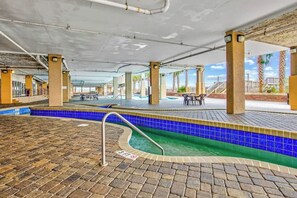 An indoor swimming pool area with tiled flooring, a diving board, and a covered seating area. - Bahama Sands Unit 0706 (North Myrtle Beach)