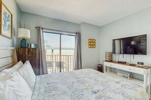 A hotel room with a bed, a TV, a desk, and a view of the sea. - Palace Resort Unit 1210 (Myrtle Beach)