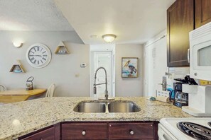 A kitchen with granite countertops, a double sink, a microwave, and a stove. - Palace Resort Unit 1210 (Myrtle Beach)