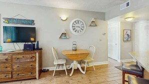 Una sala de estar con televisor, mueble de madera, mesa de comedor y sillas.