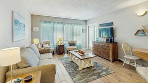 Una sala de estar con sofá, mesa de centro, televisor y aparador de madera.
