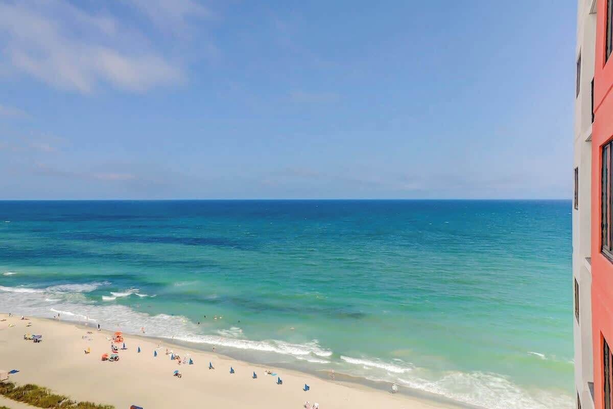 A beach with clear blue water and a sandy shore.