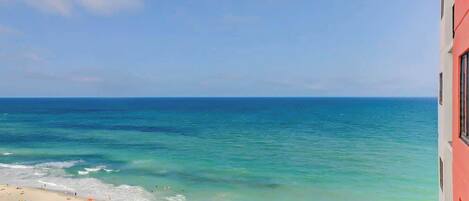 A beach with clear blue water and a sandy shore.