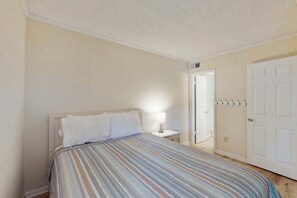 Ein Schlafzimmer mit Bett, Nachttischlampe und einer Tür mit Kleiderhaken.