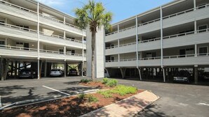 A multi-story parking garage with a central landscaped area and a palm tree. - Pelicans Watch Unit 121 (Myrtle Beach)