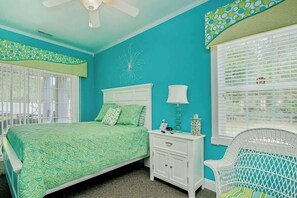 A bedroom with a bed, nightstand, chair, and a window with blinds. - K & K Getaway Retreat (Atlantic Beach)