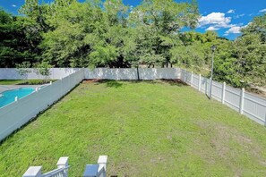 A backyard with a swimming pool, white fence, and trees. - K & K Getaway Retreat (Atlantic Beach)