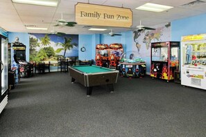 Ein Vergnügungsbereich für Familien mit Billardtisch, Spielautomaten und einer Weltkarte als Wandbild.