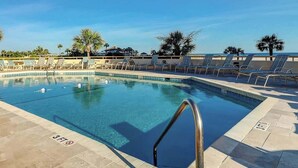 Ein Swimmingpool mit Liegestühlen und Palmen.