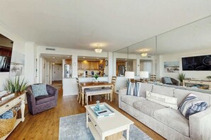 A modern living room with a sofa, coffee table, and a dining area with a table and chairs. - Ocean Creek Plantation D-1 (Myrtle Beach)