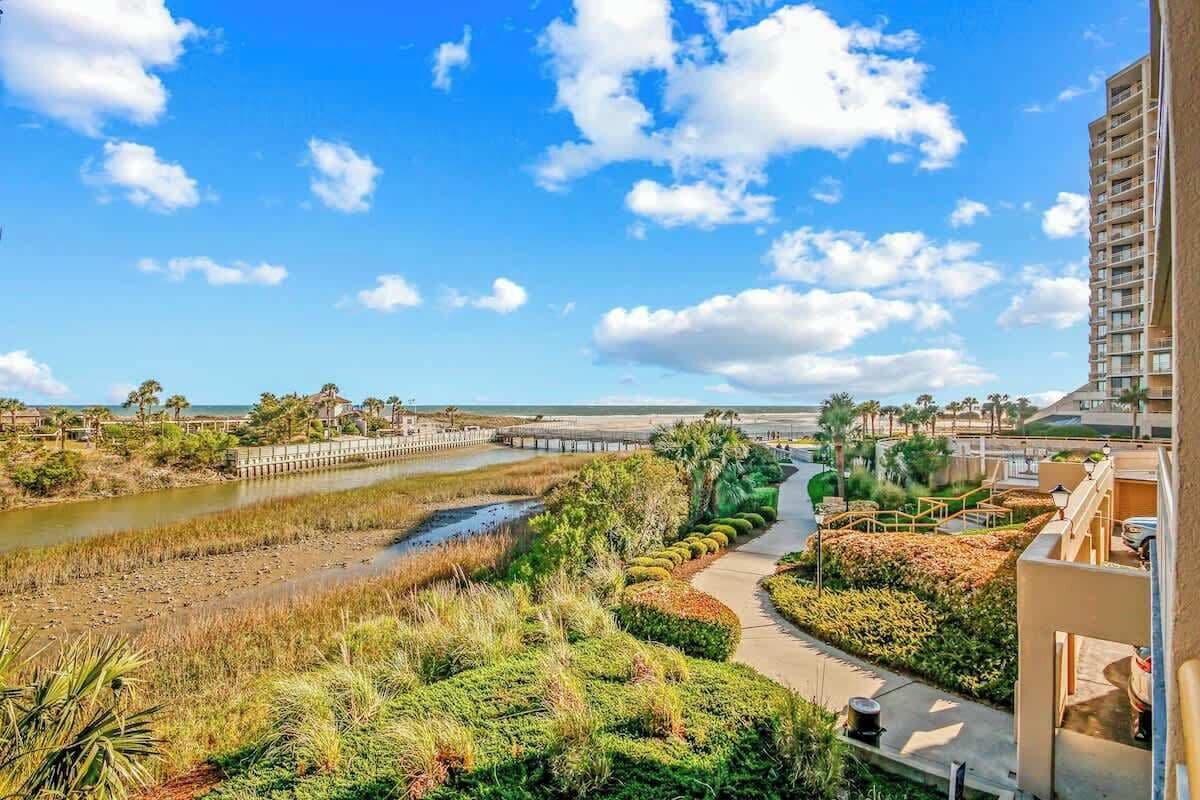 A coastal landscape with a pathway, a bridge, and a building with balconies.