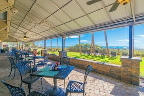 An outdoor patio area with tables and chairs, a view of the ocean, and a covered ceiling. - Ocean Reef Resort 723 (Myrtle Beach)