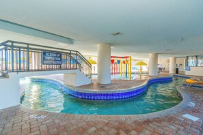 An indoor swimming pool with a no diving or jumping sign, a children's play area, and a staircase leading to an upper level. - Ocean Reef Resort 723 (Myrtle Beach)