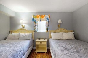 A bedroom with two beds, bedside lamps, a nightstand, and a window with curtains. - Ocean Reef Resort 723 (Myrtle Beach)