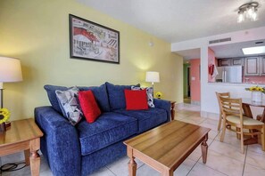 A living room with a blue sofa, wooden coffee table, and a painting on the wall. - Atlantica Resort PH51 (Myrtle Beach)