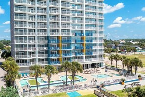 A multi-story hotel with balconies, a swimming pool area, and a landscaped garden. - Atlantica Resort PH51 (Myrtle Beach)