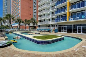 A swimming pool area with multiple levels of balconies, palm trees, and lounge chairs. - Atlantica Resort PH51 (Myrtle Beach)