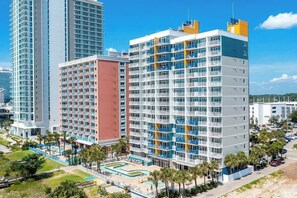 A multi-story hotel with balconies, a swimming pool, and a parking area. - Atlantica Resort PH51 (Myrtle Beach)