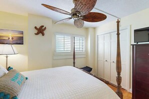 A bedroom with a four-poster bed, a ceiling fan, a starfish decoration, a painting of a beach scene, and a wardrobe. - Wellington Unit 304 Condo (North Myrtle Beach)