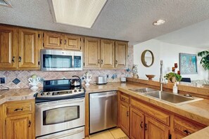 A kitchen with wooden cabinets, stainless steel appliances, a microwave, and a dishwasher. - Wellington Unit 304 Condo (North Myrtle Beach)