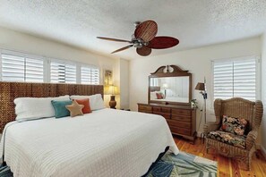 A bedroom with a large bed, a ceiling fan, a dresser, a chair, and a mirror. - Wellington Unit 304 Condo (North Myrtle Beach)