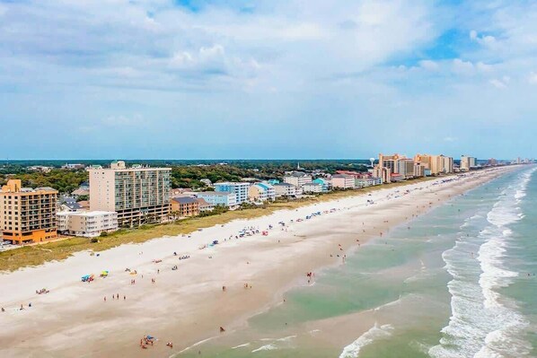 A coastal cityscape with a wide beach, high-rise buildings, and a clear sky. - Wellington Unit 304 Condo (North Myrtle Beach)