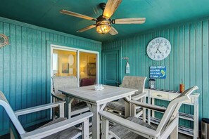 A room with teal walls, a ceiling fan, a clock, and a table with chairs. - Salty Mermaid at Wind Crest Villas (North Myrtle Beach)